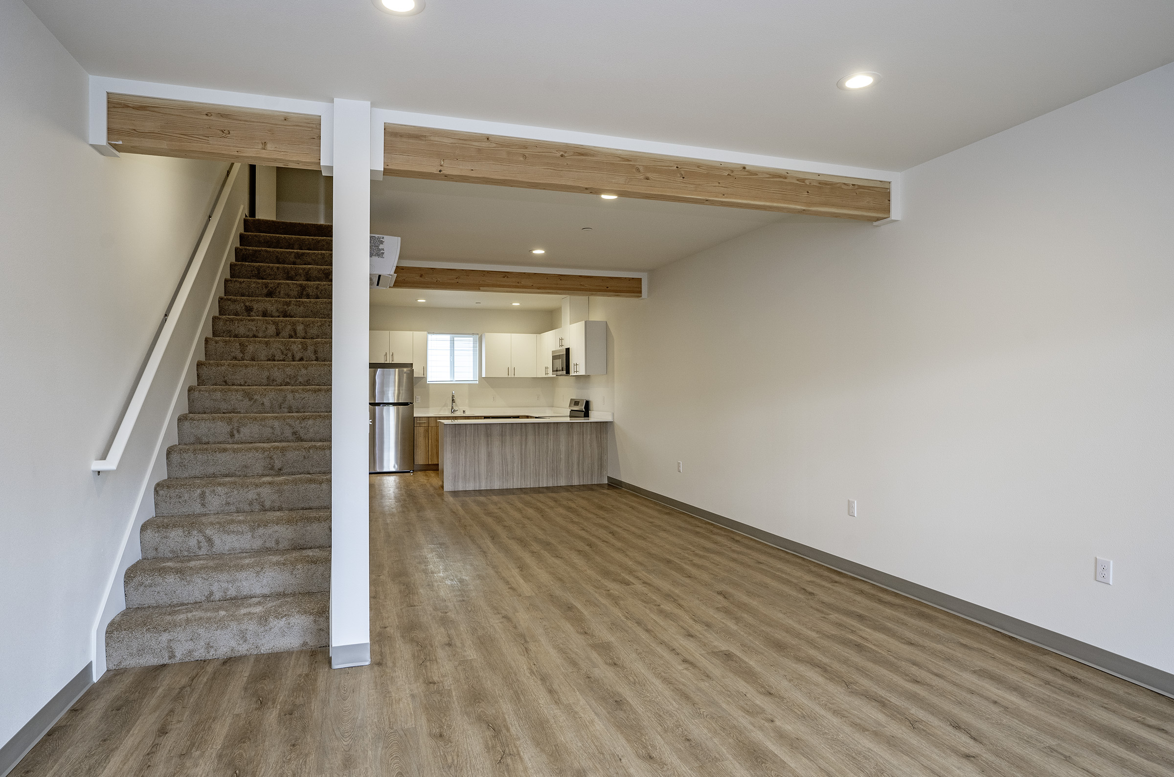 Lakewood Station open-concept living area with exposed wood beams and kitchen
